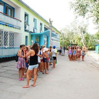 На фото: двухэтажный жилой корпус, перед домом - дети с вожатыми